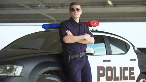 Armed Policeman in Sunglasses Standing Near Patrol Car, Dangerous Profession