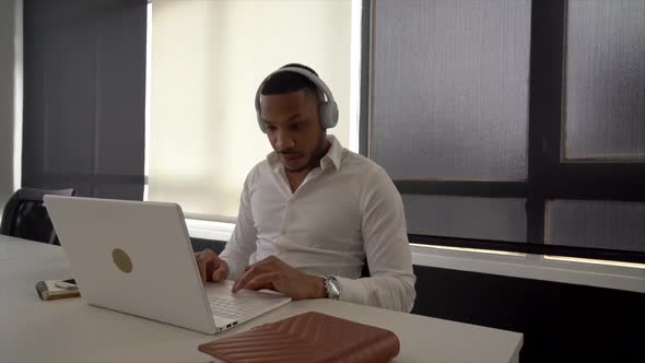Businessman with headphones using laptop in coworkoing space