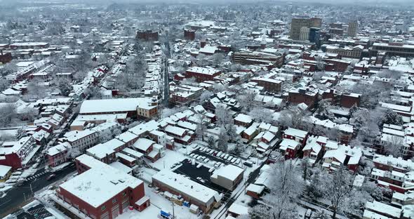 American city covered in fresh winter snow. Evening establishing shot of large town in USA. Snowy sc