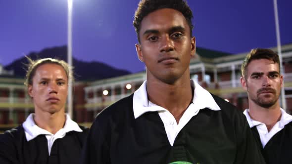 Male rugby players with rugby ball and arms crossed standing in stadium 4k