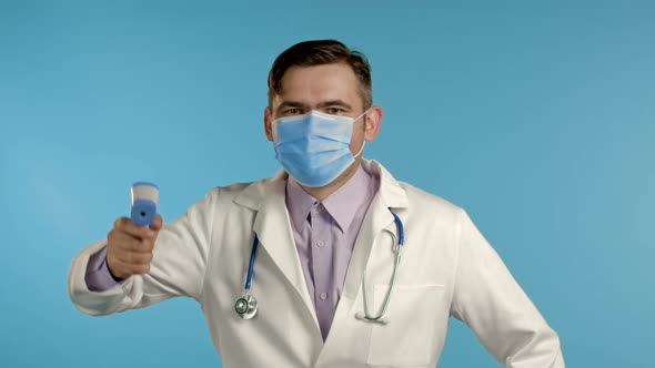 Funny Doctor in Protective Mask Directs Electronic Non-contact Thermometer Into Camera Lens 