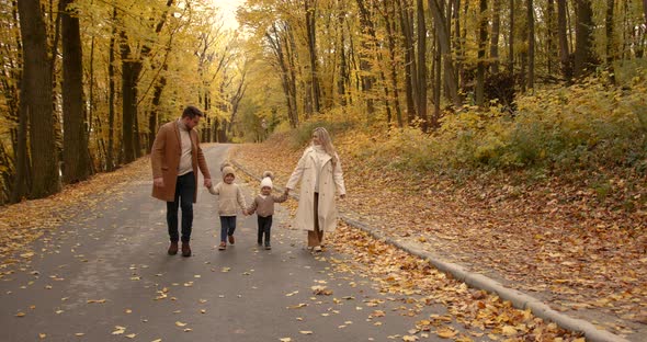 Young Family Walks Along the Road Holding Hands