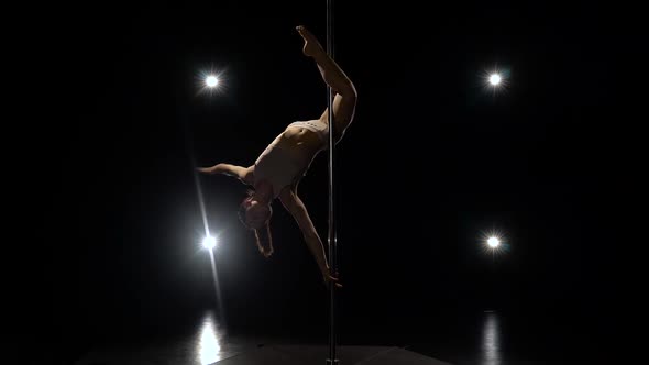 Stripper Dancing on the Pole. Black Background. Light From Behind