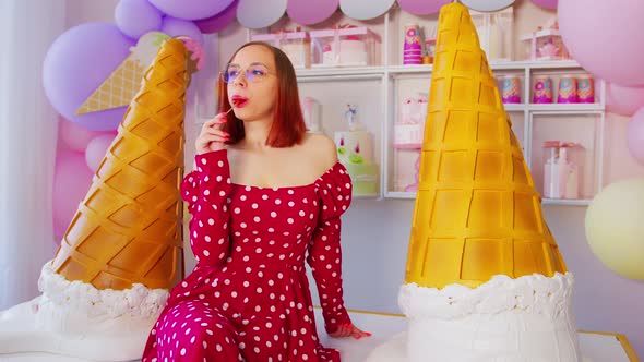 Woman eating lollipop in confectionery. 