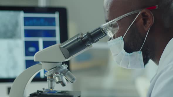 African American Scientist in Mask Using Microscope