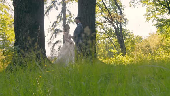 Young Couple Who Met in the Woods Near the Trees on a Background of Sunlight. The Newlyweds Gently