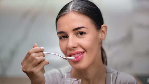 Closeup Smiling Face of Young Woman Eating Yogurt Use Spoon at Kitchen