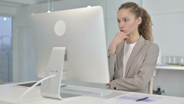 Young Businesswoman Thinking and Working on Desk Top in Office