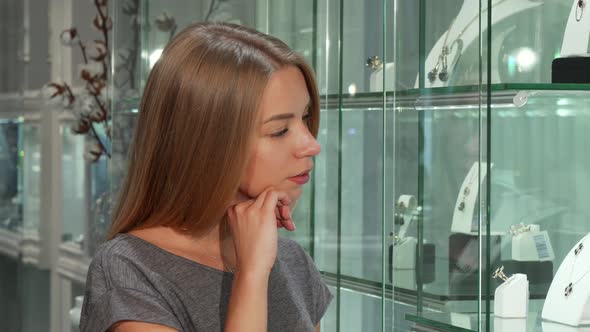 Attractive Young Female Customer Examining Display at the Jewelry Store