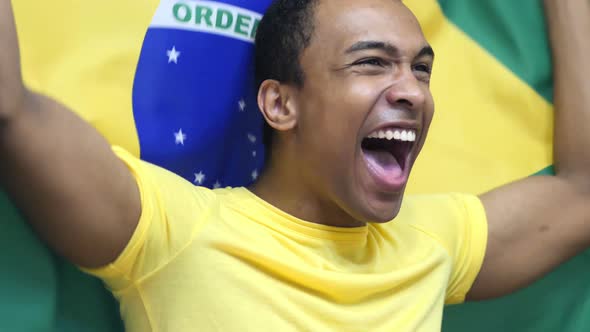 Brazilian Fan Celebrating while Holding the Flag of Brazil