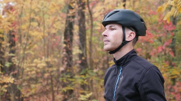 Handsome professional cyclist athlete takes off black cycling helmet and glasses after training