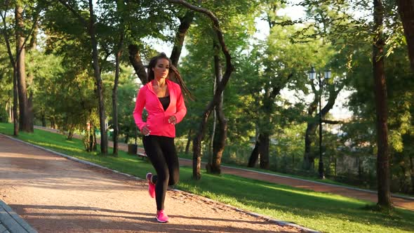 Young Woman Running in the Sunny City Park Exercising Outdoors