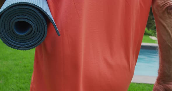 Senior man walking with a yoga mat