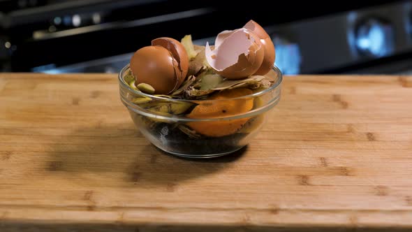 Compost material in a bowl in the kitchen on a cutting board, including eggshells, potato peels, fru