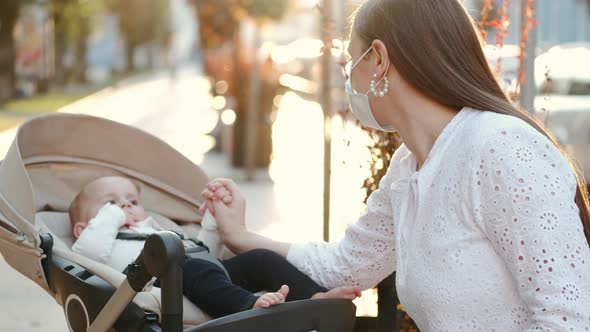 Mother Sitting on Banch with a Baby in Pram and Read Papers