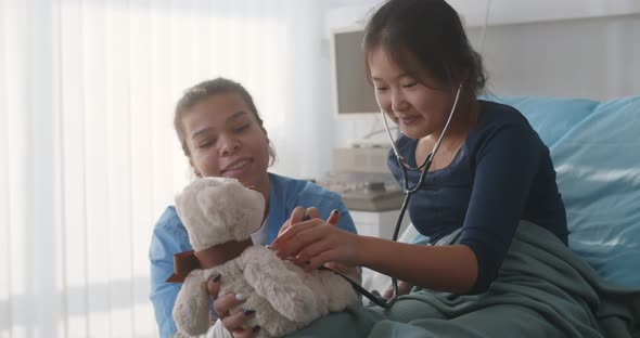 Mixed Race Nurse Playing with Sick Asian Kid Patient in Hospital Ward