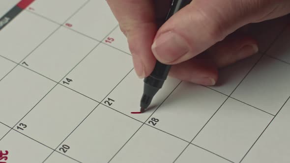 Close Up of Female Hand Marking the Day in Calendar By Writing PARTY As a Reminder Using a Red Pen