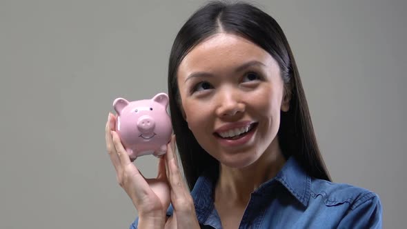 Young Asian Woman Shaking Piggy Bank, Saving Money and Investment, Close Up