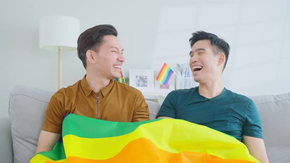 Portrait of Asian handsome man gay family holding LGBT flag and smile.