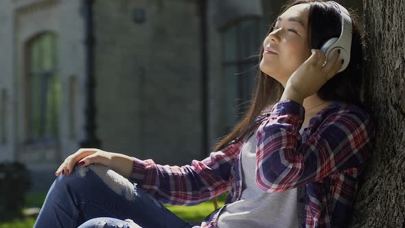 Beautiful Happy Student Enjoying Favorite Music That Sounds in Her Headphones