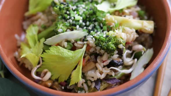 Asian Dish of Rice and Vegetables Sprinkled with Sesame Seeds and Herbs Closeup