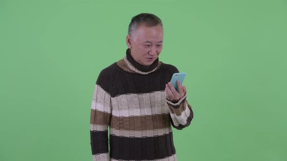 Happy Mature Japanese Man Using Phone and Looking Surprised