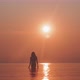 Silhouette of a young woman clumsily walking in the sea with the sunrise in the background - VideoHive Item for Sale