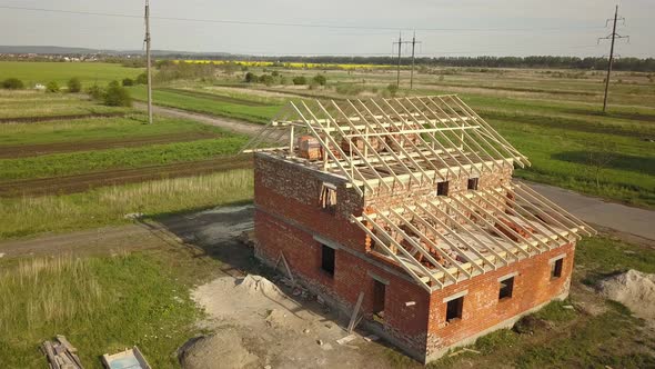 Aerial View of Unfinished Brick House with Wooden Roof Frame Structure Under Construction