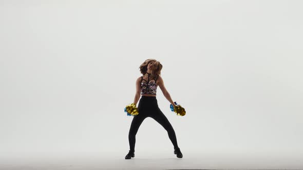 Silhouette of Slender Cheerleader in Shiny Top and Leggings Dancing Energetically with Pompoms in