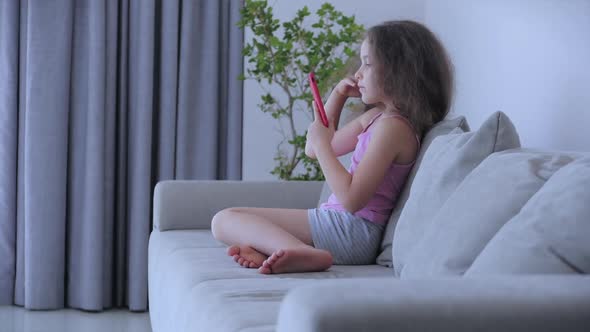 Curious Cute Girl Preschool Child Using a Digital Tablet Technology Device Looks telephone