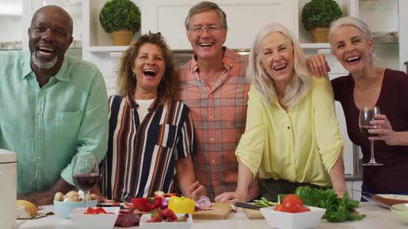 Animation of happy diverse female and male senior friends preparing meal in kitchen