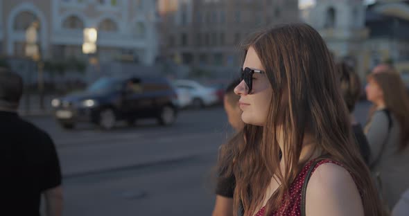 A Girl with Long Hair Stands in Front of the Road on Which Cars are Driving