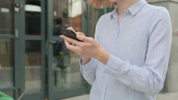 Woman Using Smartphone While Walking in Street