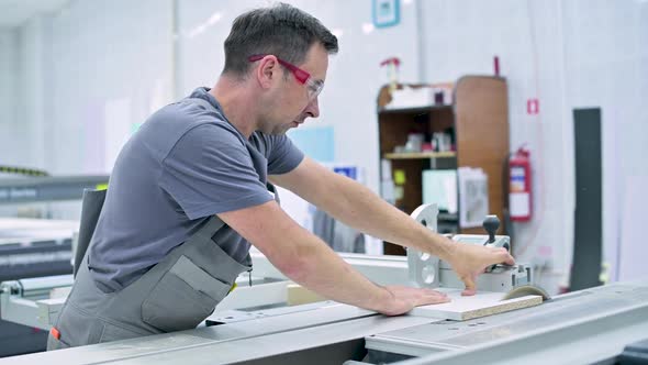 A man works in the assembly shop on a circular saw, neglecting safety