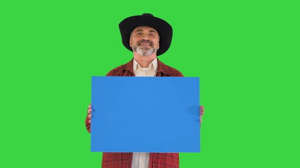 Smiling Senior Man in a Hat Holding Blank Placard on a Green Screen, Chroma Key.