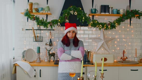 Disappointed Female in Red Santa Hat Folding Hands While Standing Near Served Dining Table and