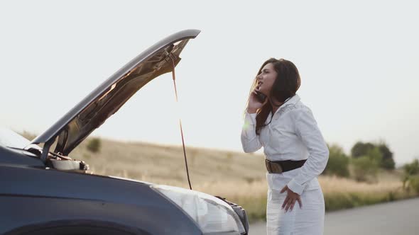 Worried Business Lady Talking on Phone at Open Car Hood on Sunset Out of City