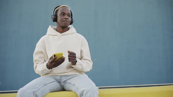 Trendy African American Man Using Smartphone to Listen to Music Song on Headphones