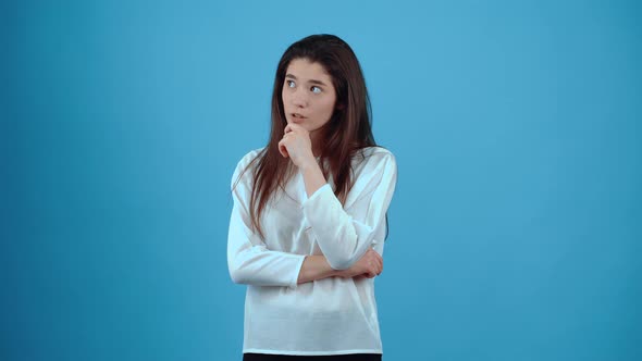 The Young Woman Thinking with Her Hand on Her Chin Looks in Parts and Thinks How to Proceed What to