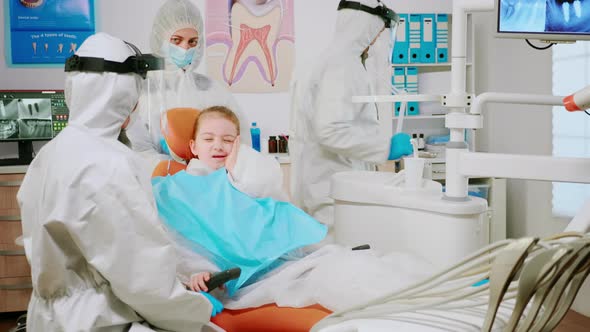 Child Wearing Protection Suit Using Finger To Point Affected Tooth