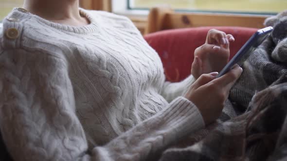 A Woman Uses a Smartphone on the Couch at Home.