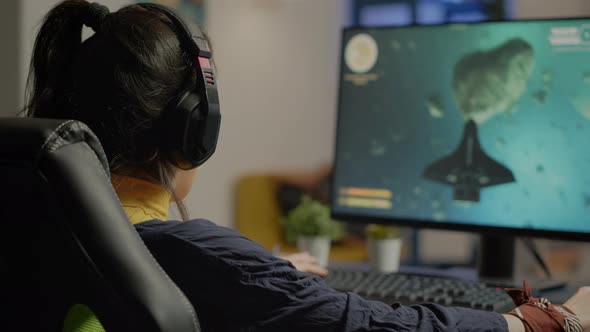 Focused Woman Gamer Sitting on Desk Putting on Headset