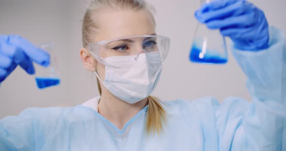 Female Scientist Holding Tubes and Flask with Liquid in Hands alt