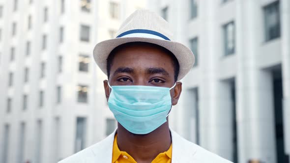 Black guy in classic suit with fedora hat and blue disposable face mask