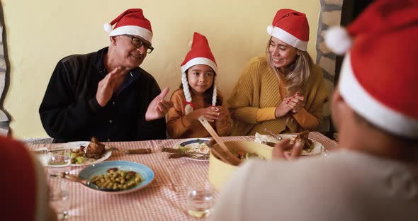 Happy latin family celebrating christmas and eating dinner together at home