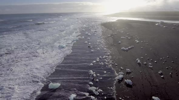 Aerial view of black sand beach with iceberg ice pieces on the shore also cal