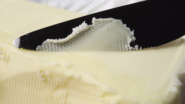 Farm butter is cut with a serrated knife in a thin layer