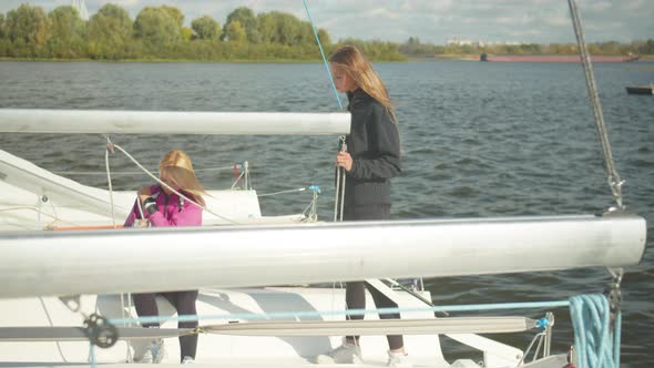 End of the Sailing Season. On a Cold Autumn Day, Female Sailing Athletes Dismantle the Rigging of