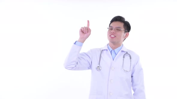 Happy Young Asian Man Doctor Presenting and Pointing Up