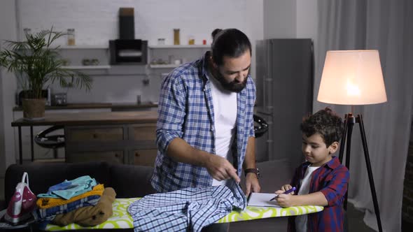 Dad Busy with Housework Helping Son with Homework